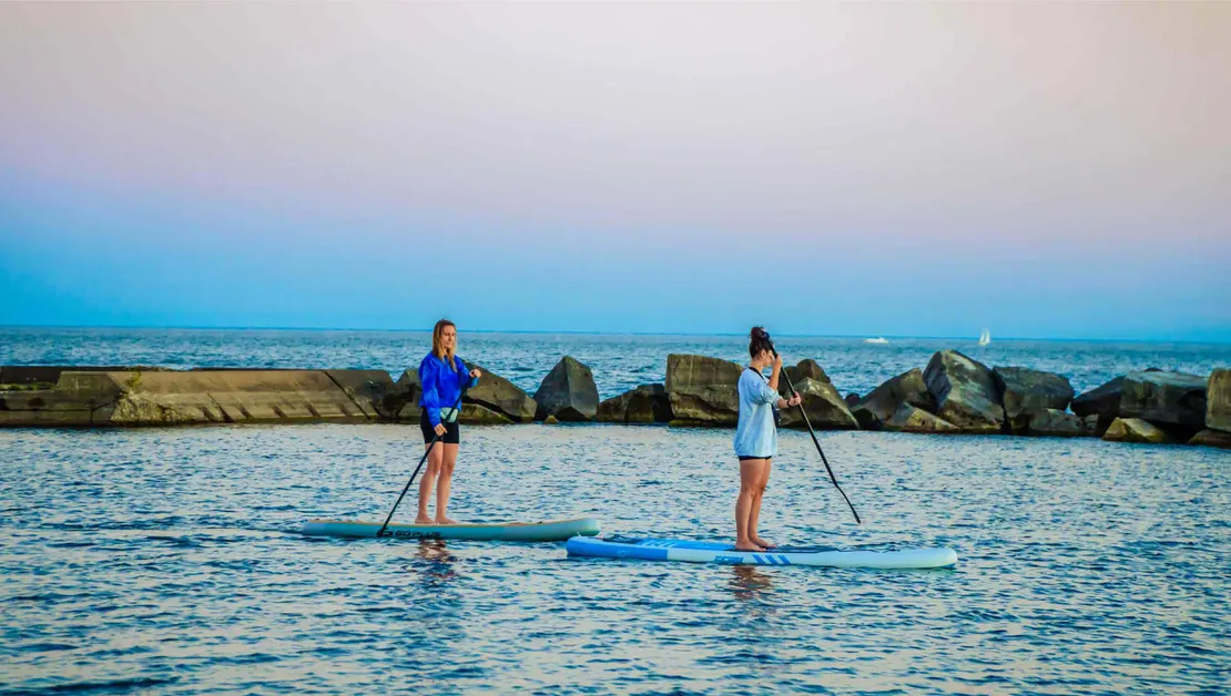 Two women stand up paddling in Lake Ontario, Toronto.