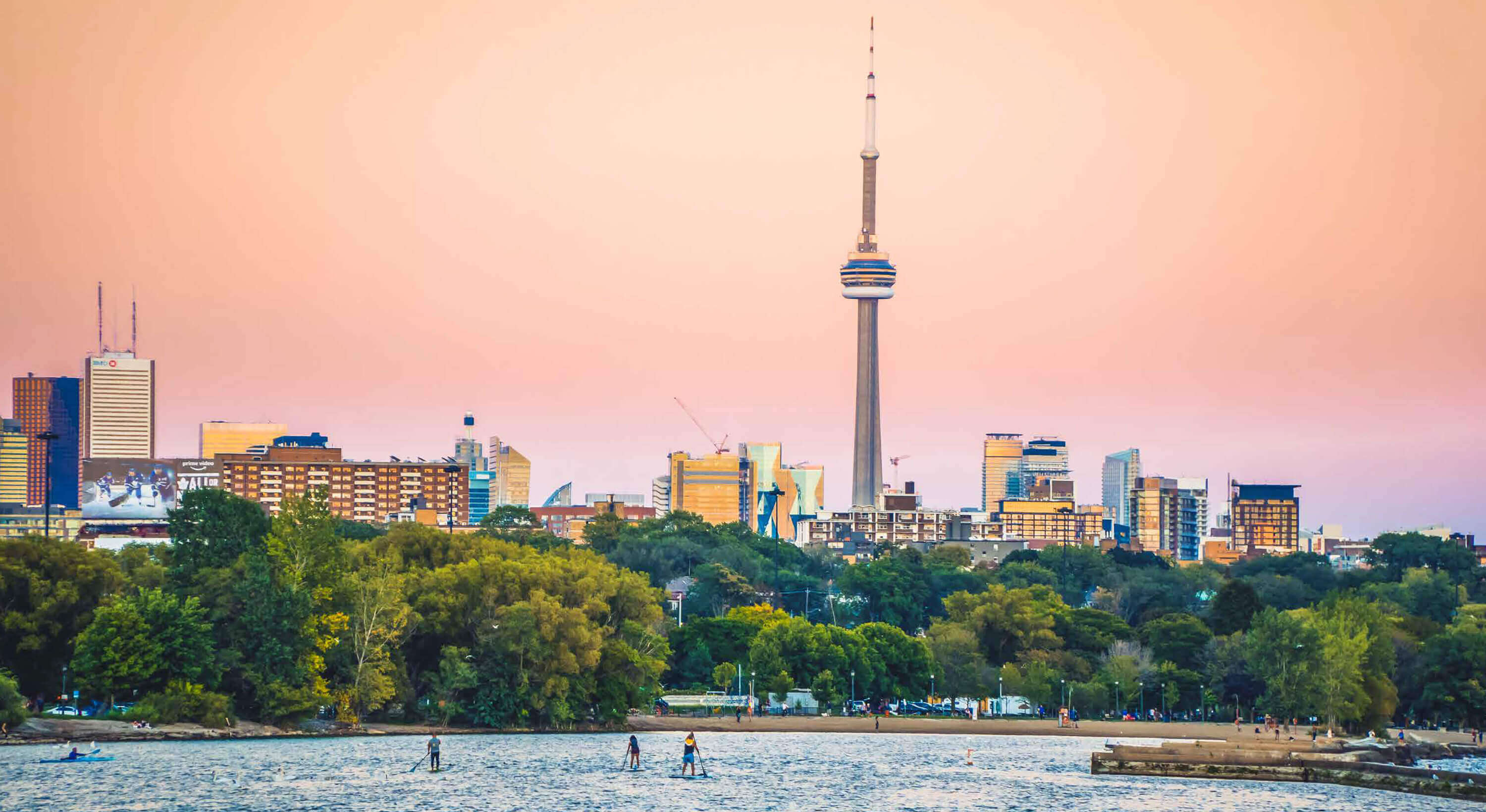 Kayakers, paddle boarders enjoy Lake Ontario, CN Tower and Toronto skyline in the backdrop.